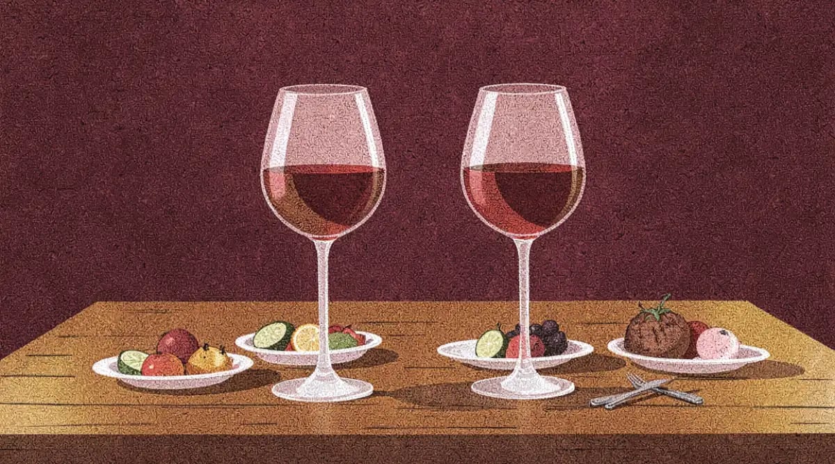 Copa de vino tinto junto a ofrenda de Día de Muertos con pan de muerto, cempasúchil y velas